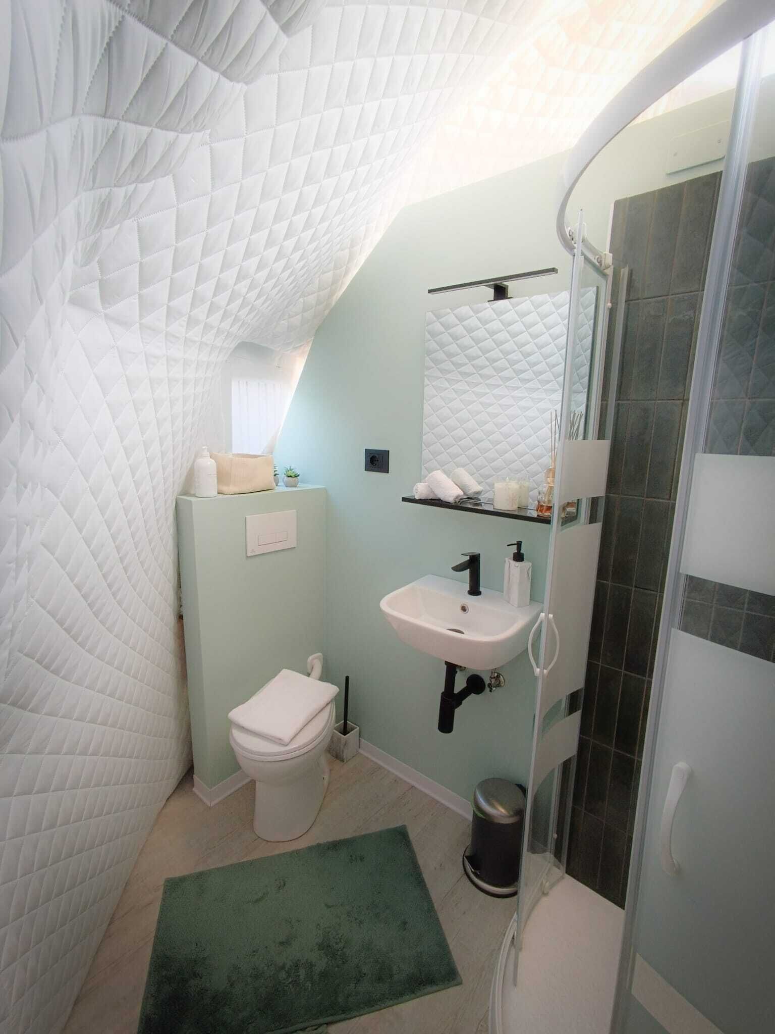 Un baño pequeño con inodoro blanco, lavamanos y zona de ducha.