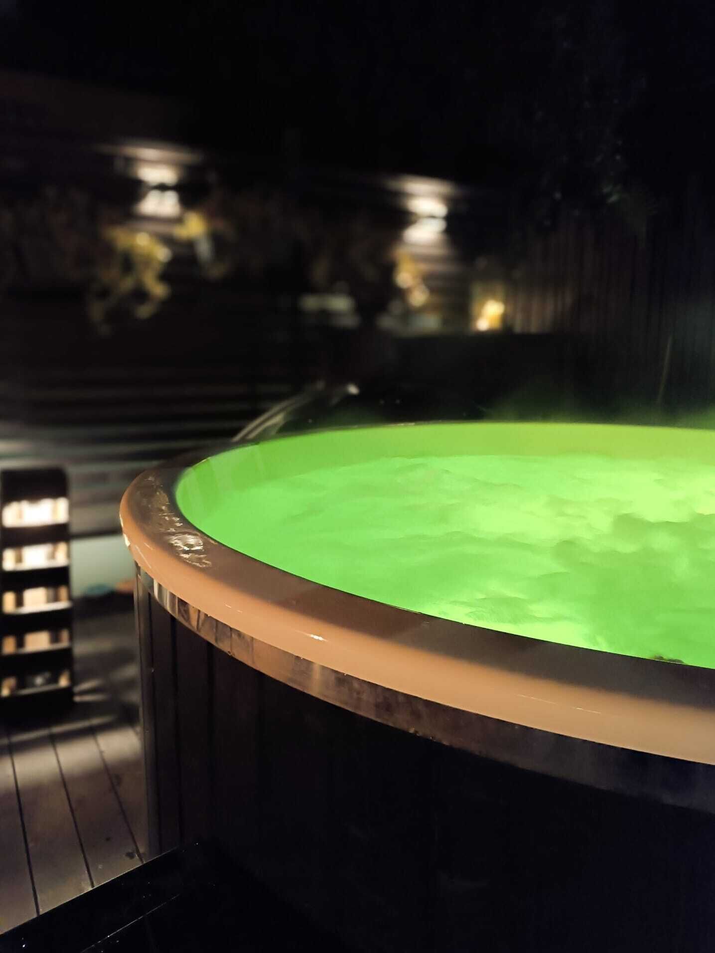 Un bain à remous à l’intérieur verdoyant, entouré d’une terrasse en bois.