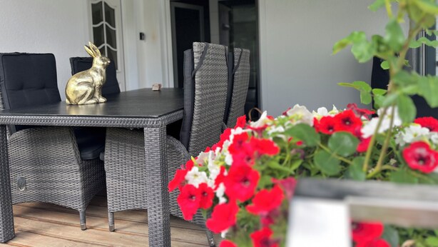 A dining area with wicker furniture, a table with a golden rabbit figurine, and a potted plant with red flowers. - Super nice and completely renovated vacation home between Szczecin Lagoon and Usedom (Ducherow)