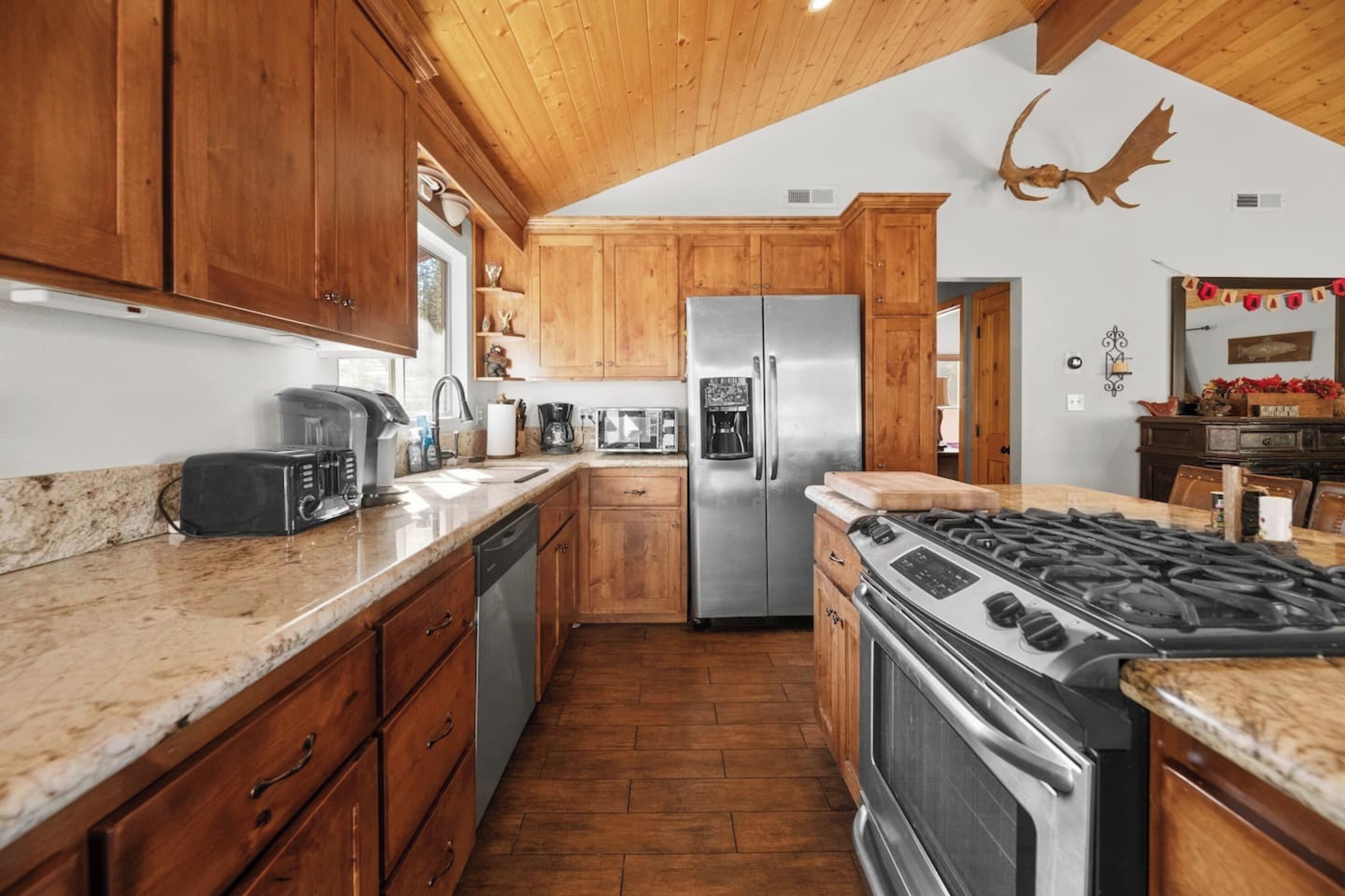 A kitchen with wooden cabinets, a stainless steel refrigerator, a gas stove, and a microwave.