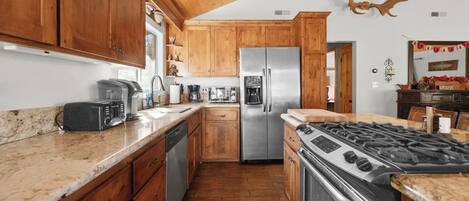 A kitchen with wooden cabinets, a stainless steel refrigerator, a gas stove, and a microwave.