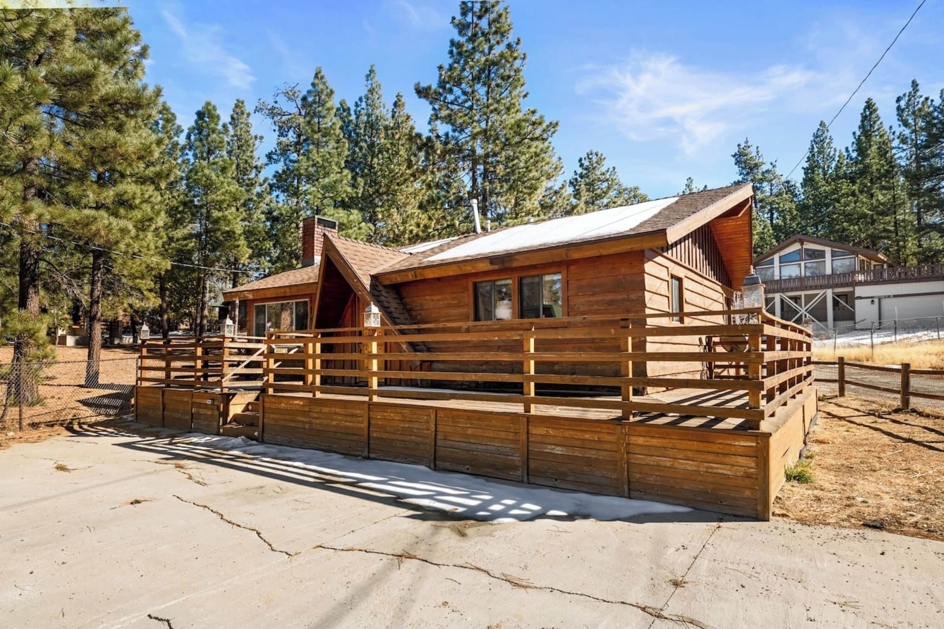 Una cabaña de madera con terraza amurallada, rodeada de árboles.