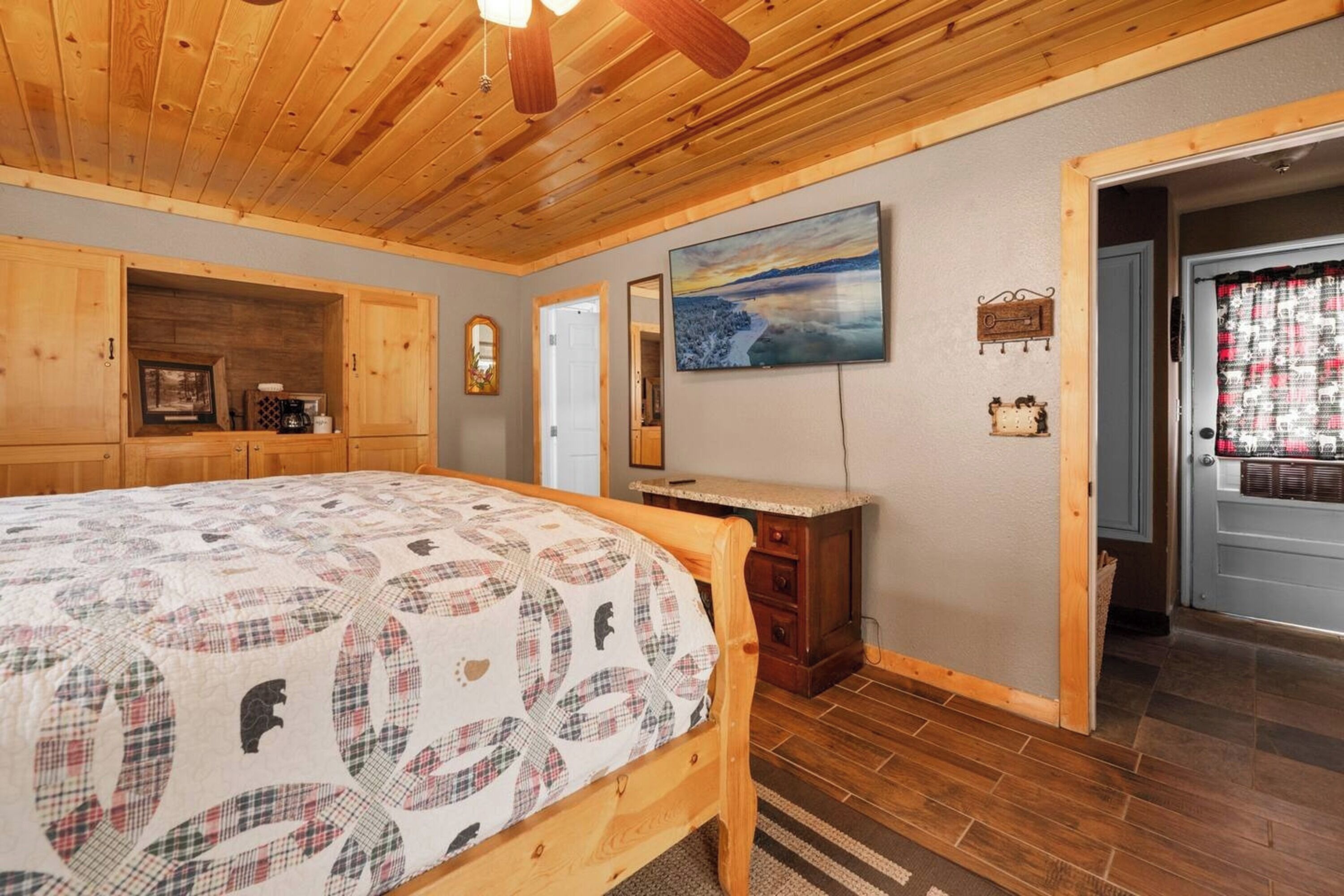 Une chambre à coucher avec un lit en bois, une table de chevet, une commode et un tableau accroché au mur.