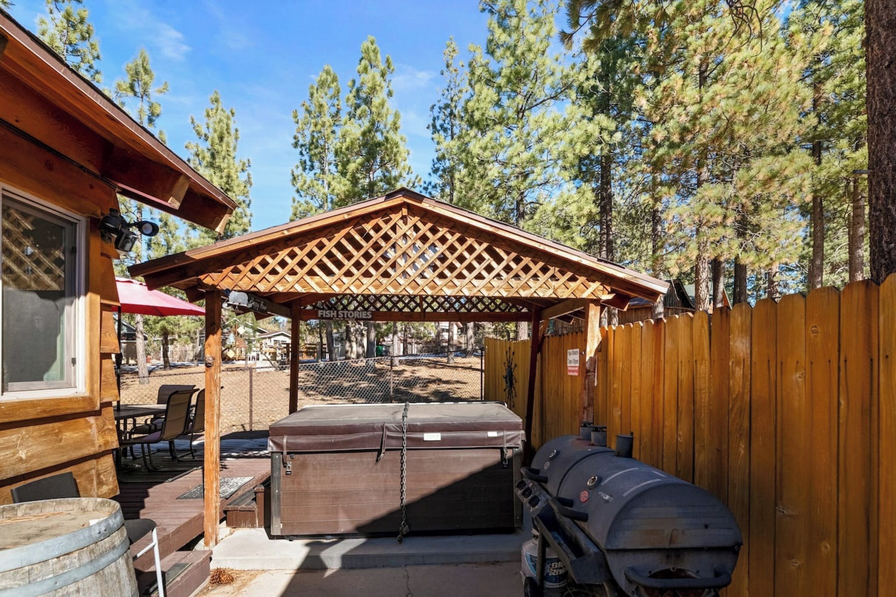 A wooden deck with a barbecue grill, a covered seating area, and a wooden fence.
