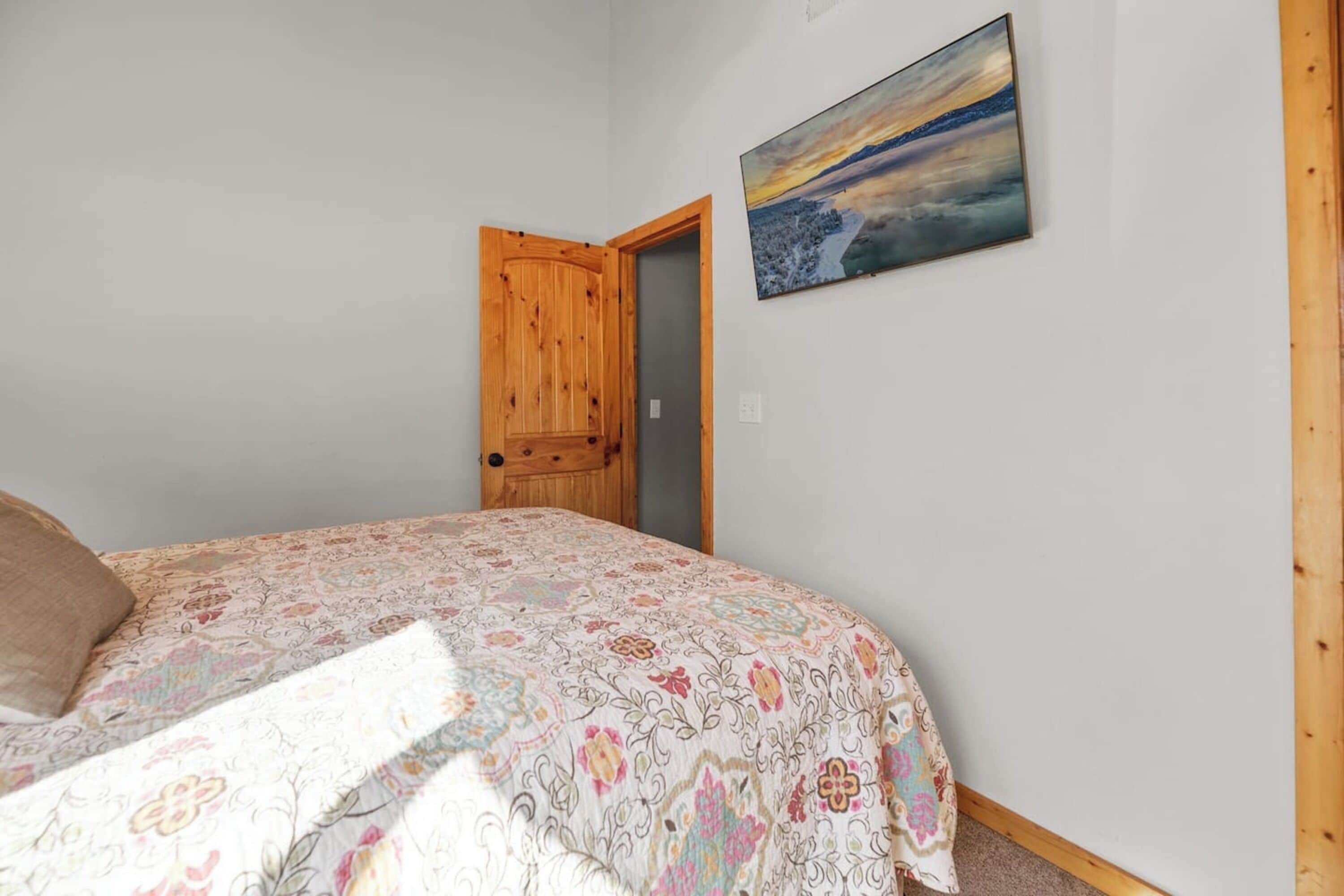 Ein Schlafzimmer mit einem Bett, einer Holztür und einem Bild an der Wand.