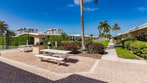 A paved outdoor area with picnic tables, a basketball court, and a pool. - 05 Standard Plus - Screened Lanai (Siesta Key)