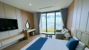 Habitación de hotel moderna con una cama grande, un escritorio, una silla, un televisor y vistas a la ciudad.