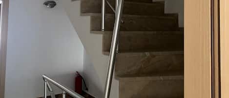 Un escalier doté d’une rampe métallique et d’un panneau indiquant la sortie.