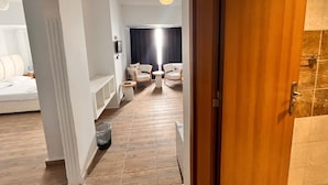 Ein Hotelzimmer mit einem Bett, einer kleinen Sitzecke mit Stühlen und einem Tisch, einem Mülleimer und Holzboden.
