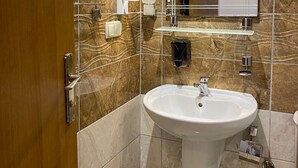 Ein Badezimmer mit Marmorwand, Waschbecken, Spiegel und Handtuchspender.