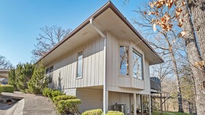 A two-story house with a gabled roof, large windows, and a covered porch area. - Treetop Trailhaven-Direct Access to MTB Trails! (Bella Vista)