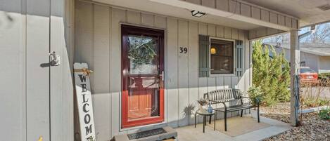 A house with a red door, a welcome sign, and a bench outside.