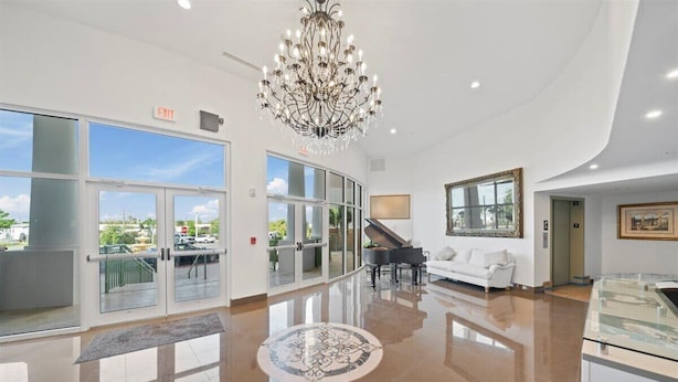 A spacious lobby with a grand chandelier, a piano, a white sofa, and a glass display case. - RIVER FLY IN: Garden View (Merritt Island)