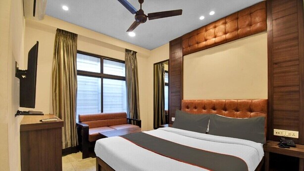 A hotel room with a large bed, a desk, a sofa, and a ceiling fan. - Shankar Guest House (Kolkata)