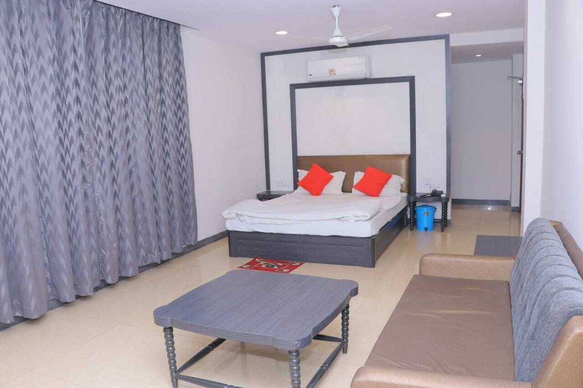 Una habitación de hotel con cama, sofá, mesa de centro y cortina.