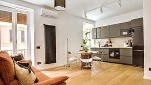 A modern apartment with a living area featuring a sofa and a dining table. - Cereate Suites (Rome)
