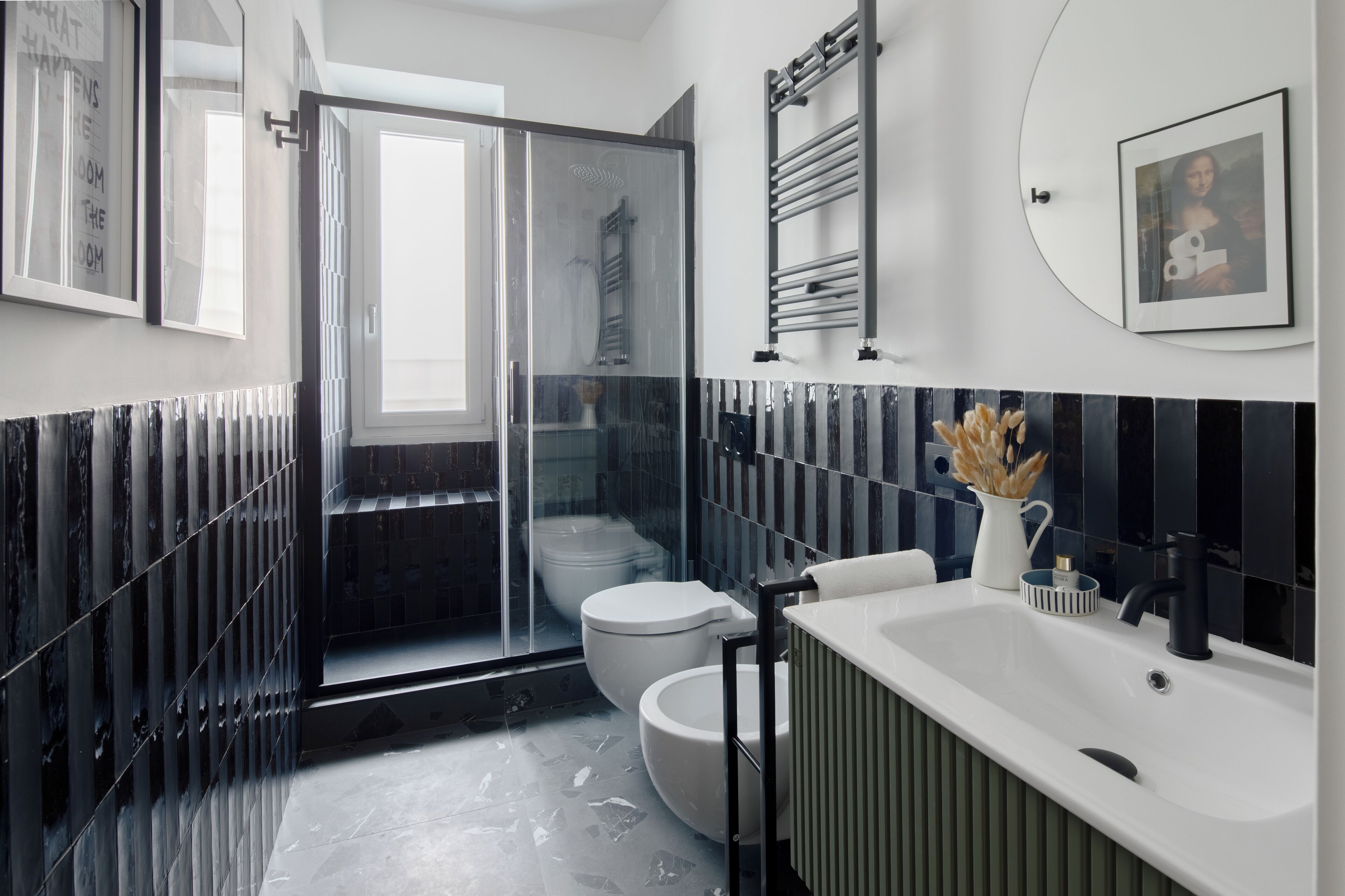 A modern bathroom with a glass-enclosed shower, a white toilet, a black bathtub, and a white sink.