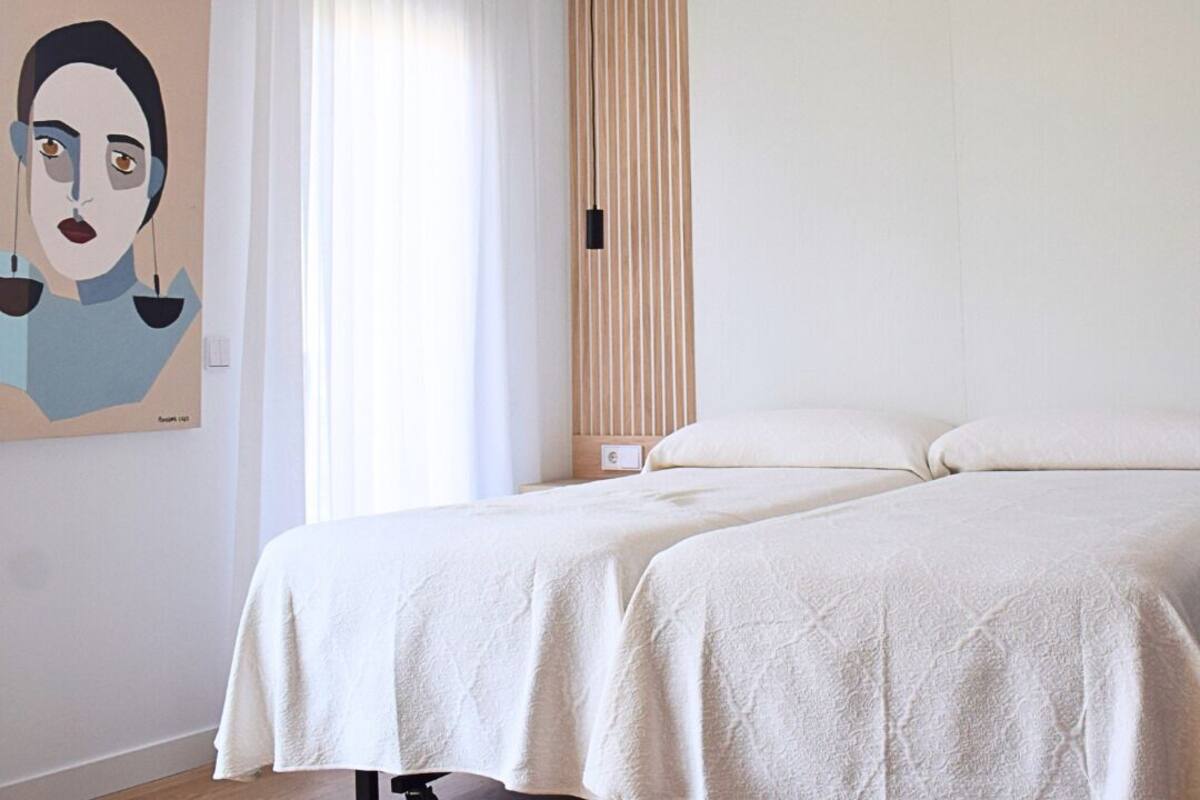 Un dormitorio moderno con cama, un cuadro y una ventana con cortinas.