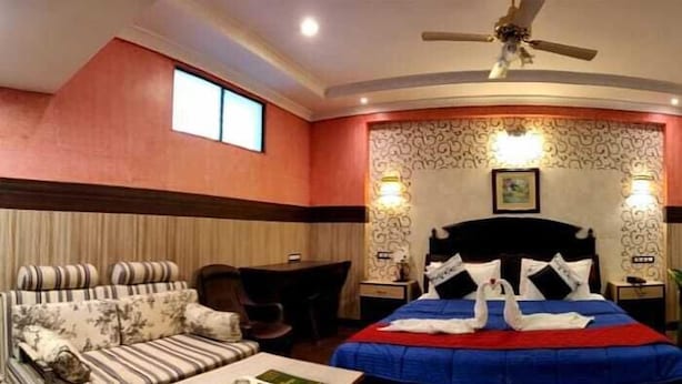 A hotel room with a bed, sofa, and a small table. - Hotel Nala Residency (Tiruvannamalai)