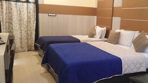 A hotel room with two beds, a desk, and a chair. - Hotel Nala Residency (Tiruvannamalai)