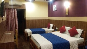 A hotel room with two beds, a wooden table, and an air conditioning unit. - Hotel Nala Residency (Tiruvannamalai)