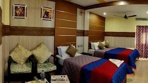 A hotel room with two beds, a sofa, and a ceiling fan. - Hotel Nala Residency (Tiruvannamalai)