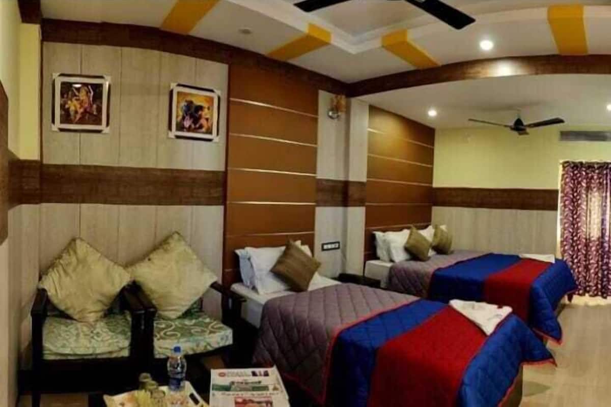 Habitación de hotel con dos camas, un sofá y un ventilador de techo.