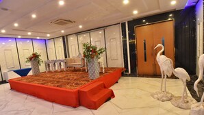 A hotel lobby with a stage, seating, and decorative statues. - Foxoso Fiori Hotel (Jaipur)
