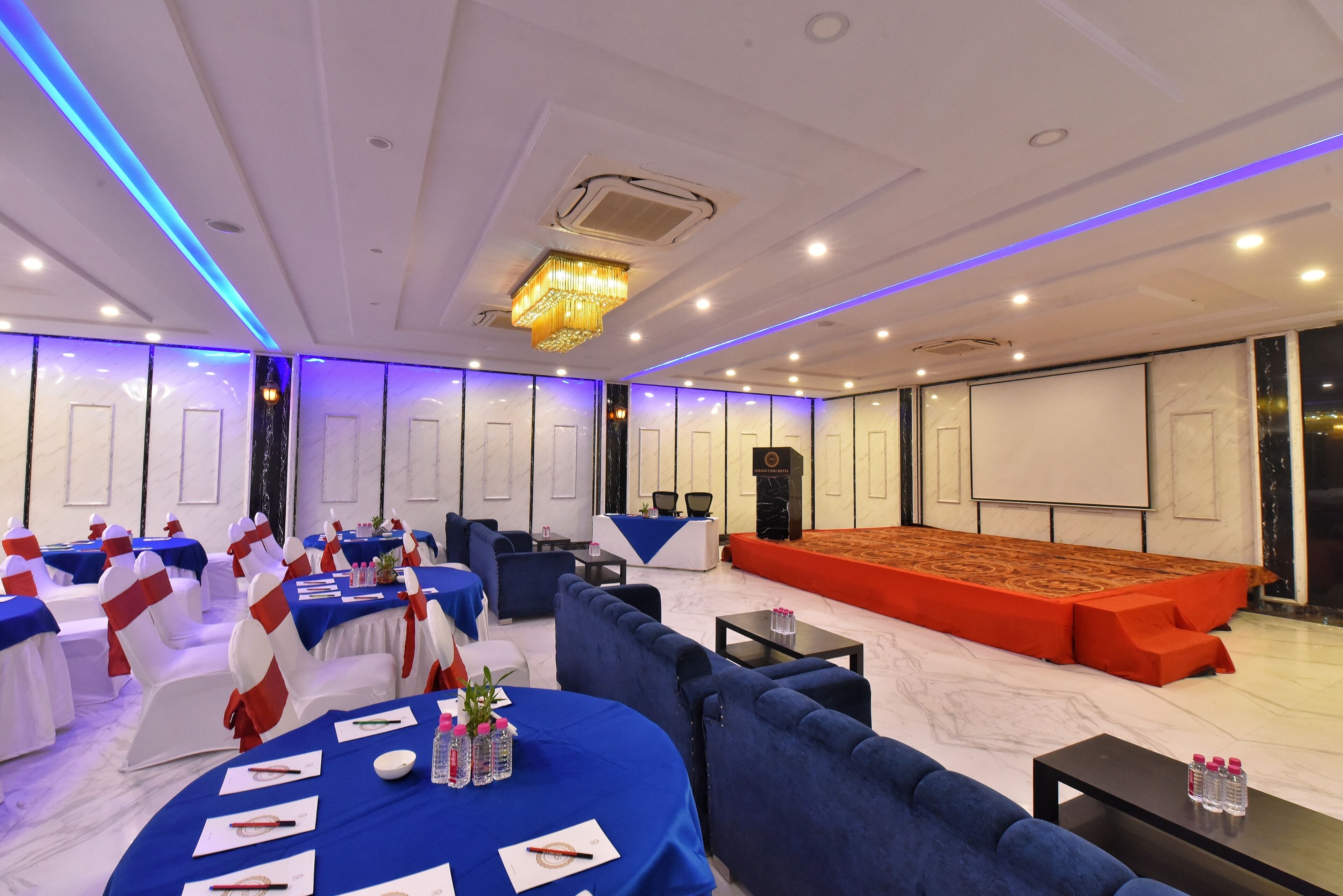 Un salón de conferencias con escenario, asientos y mesas.