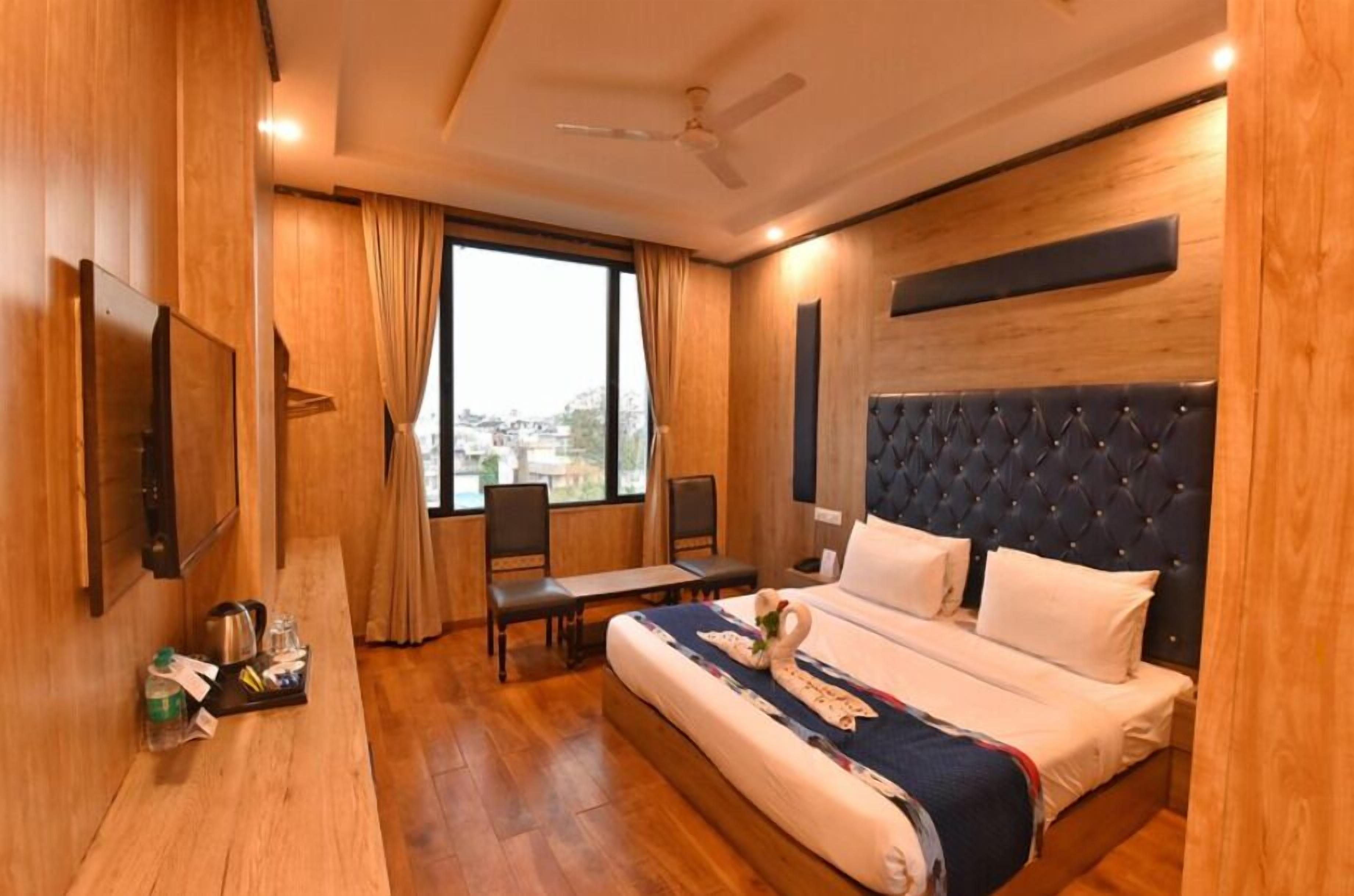 A hotel room with a bed, a desk, a chair, a window, and a ceiling fan.