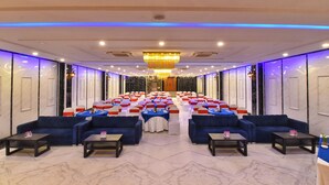 A conference room with rows of tables and chairs, a chandelier, and blue sofas. - Foxoso Fiori Hotel (Jaipur)