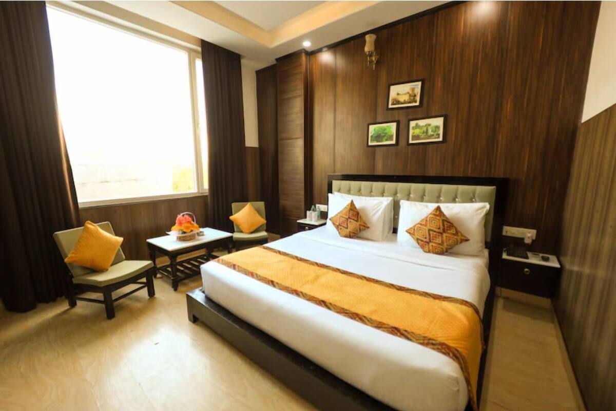 A hotel room with a large bed, a desk, a chair, and a window.