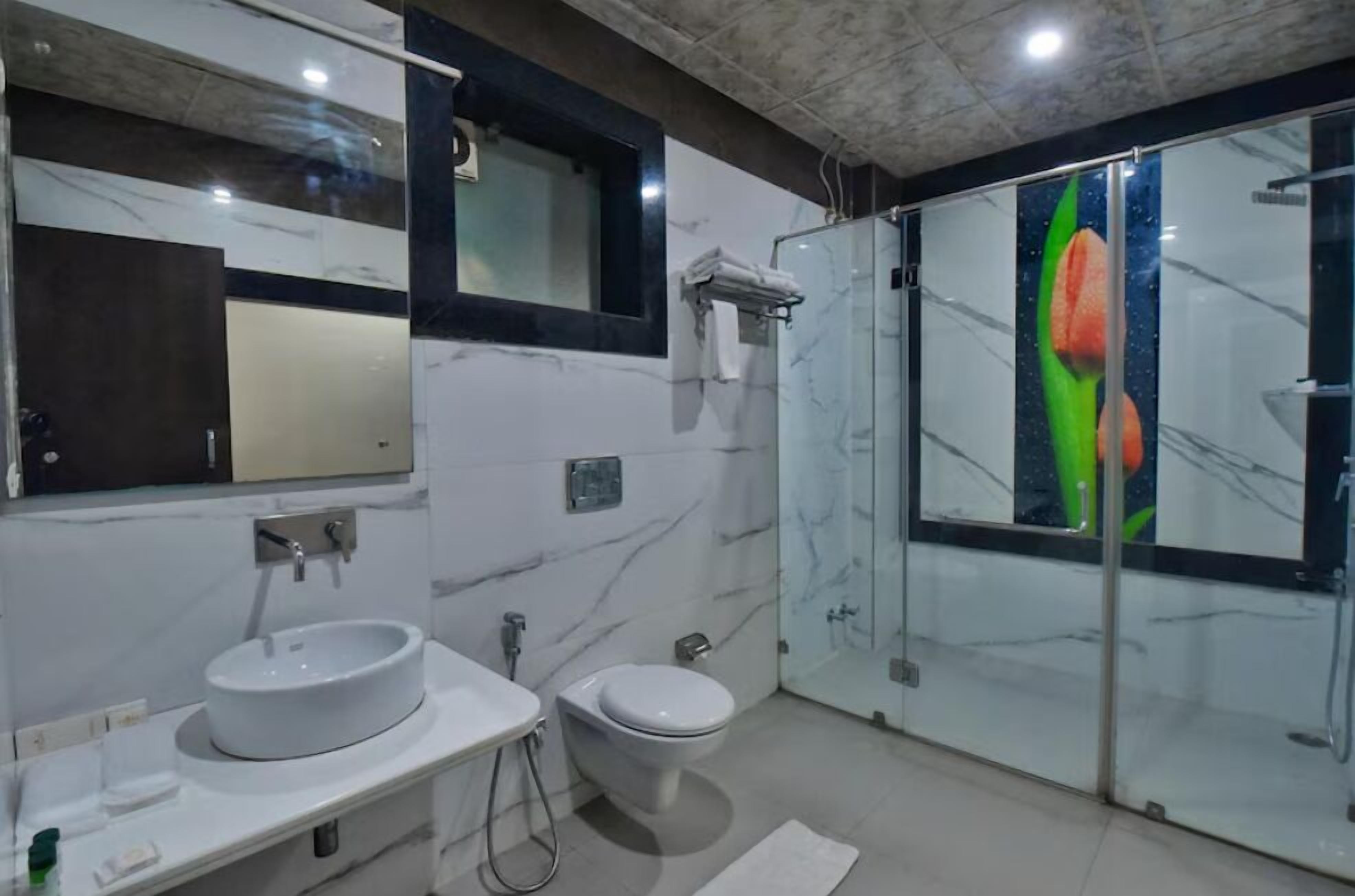 A modern bathroom with a marble vanity, a toilet, and a glass shower enclosure.