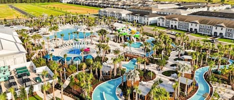 Un resort con varias piscinas, palmeras y edificios residenciales.