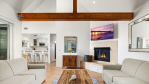 Una sala moderna con chimenea, un comedor y una cocina al fondo.