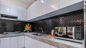 A modern kitchen with white cabinets, a black tiled backsplash, a built-in stove, and a sink. - Villa Rama (by JB Villas) (Bali)