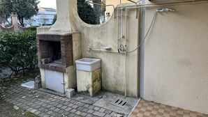 An outdoor kitchen with a brick oven, a sink, and a hose for water. - Villaggio Tivoli 6-c13 (San Michele al Tagliamento)