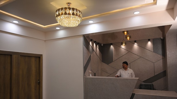 A reception area with a wooden door, a modern reception desk, and a chandelier. - The Govindam Resort (Vrindavan)