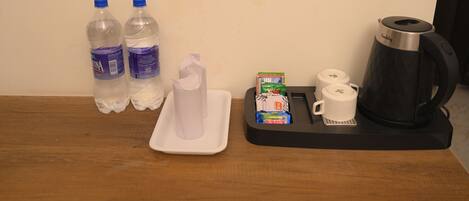 A table with two water bottles, a tissue, a tray with coffee cups and a coffee pot.