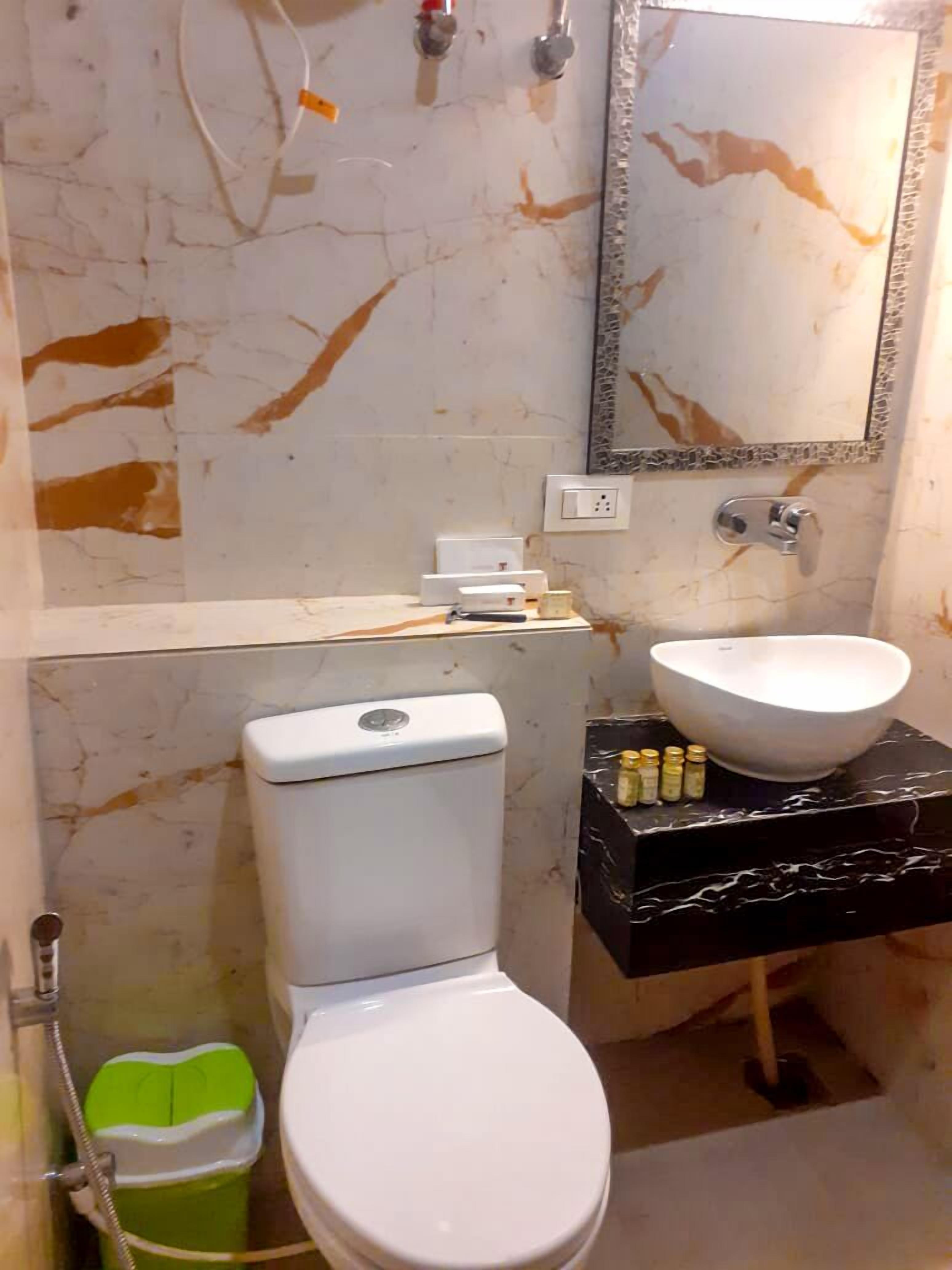 A bathroom with a toilet, sink, and mirror.