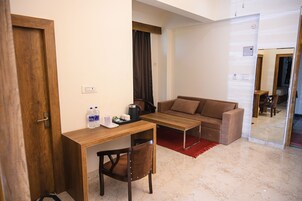 A compact living space with a wooden desk, a brown sofa, and a red rug.