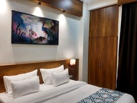 Una habitación de hotel con una cama grande, cabecera de madera, un cuadro colgado en la pared y un armario.