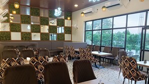 A restaurant with a modern interior, featuring a mix of seating arrangements, including booths and tables. - The Govindam Resort (Vrindavan)