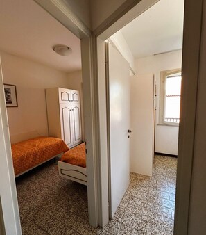 A bedroom with a bed, wardrobe, and a door leading to another room.