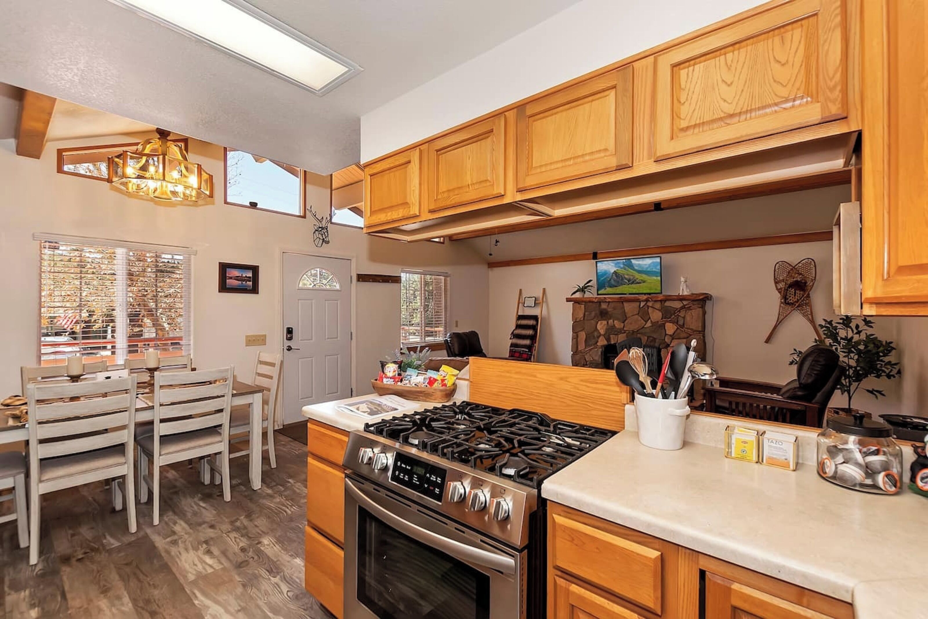 A kitchen with wooden cabinets, a gas stove, a dining table with chairs, and a chandelier.