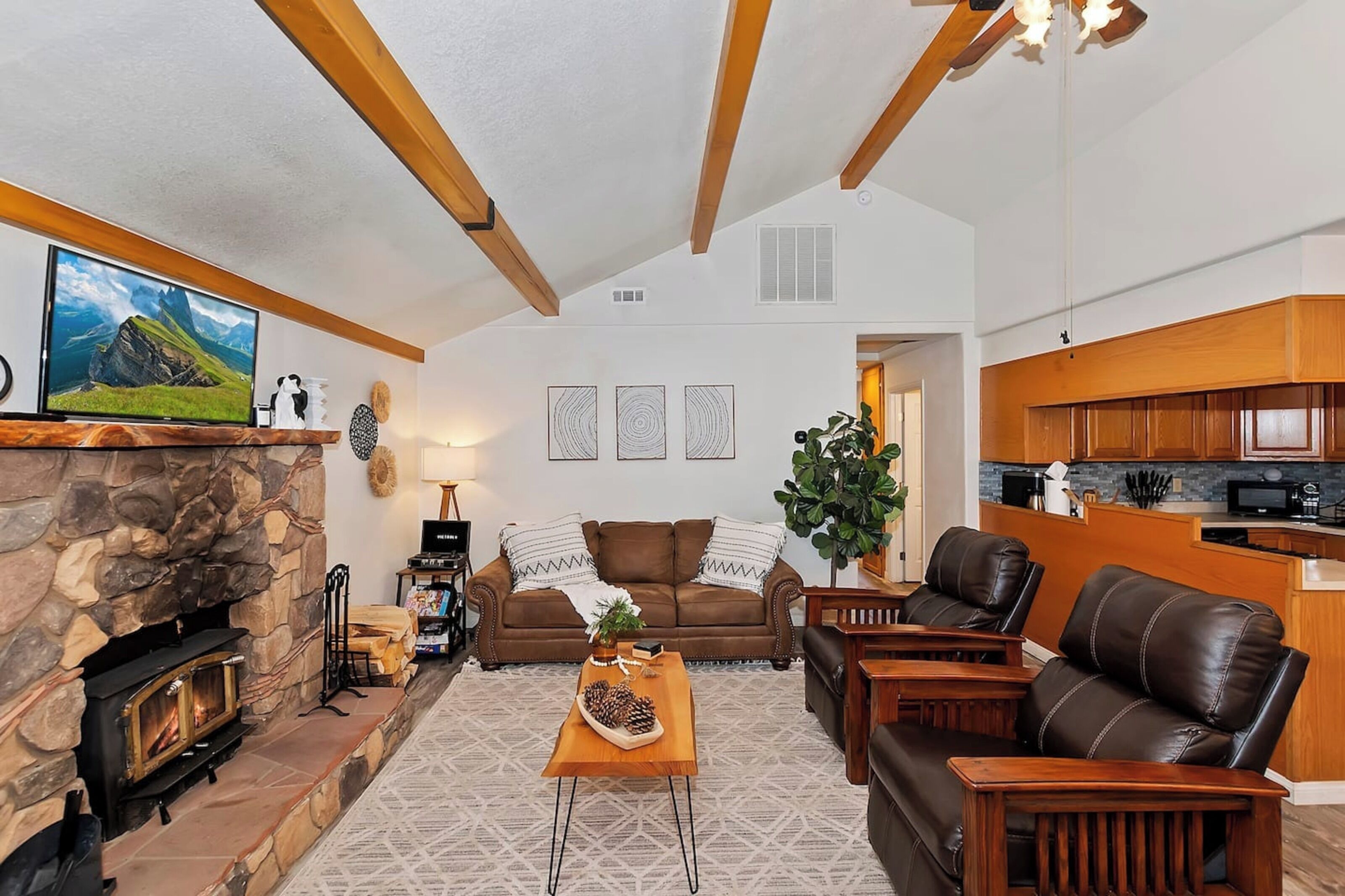 A cozy living room with a stone fireplace, a comfortable sofa, a coffee table, and a television.