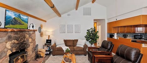 A cozy living room with a stone fireplace, a comfortable sofa, a coffee table, and a television.