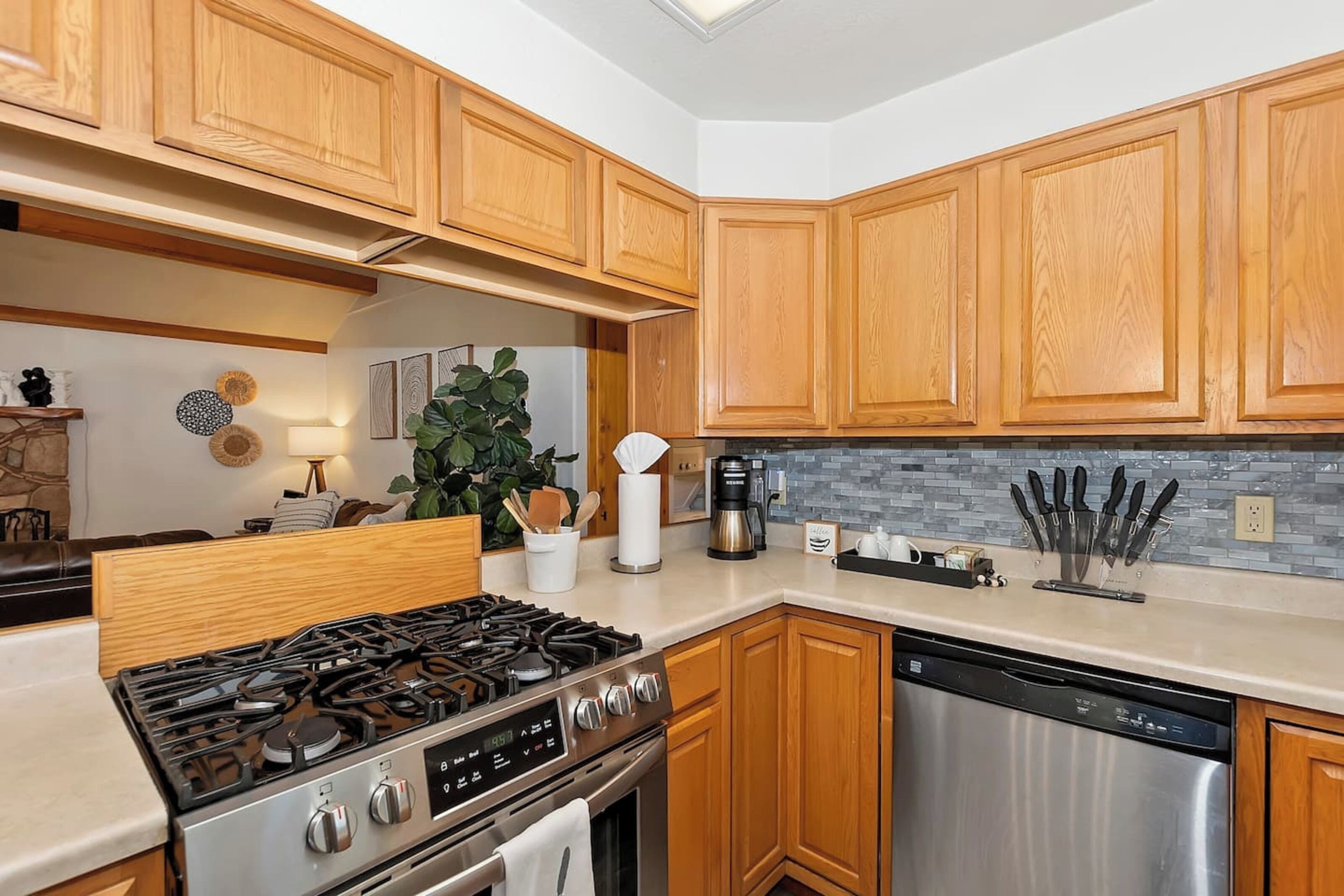 A kitchen with wooden cabinets, a stainless steel stove, and a dishwasher.