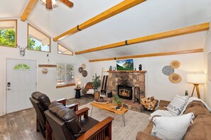Un salon chaleureux avec une cheminée, des canapés en cuir et un plafond en bois.