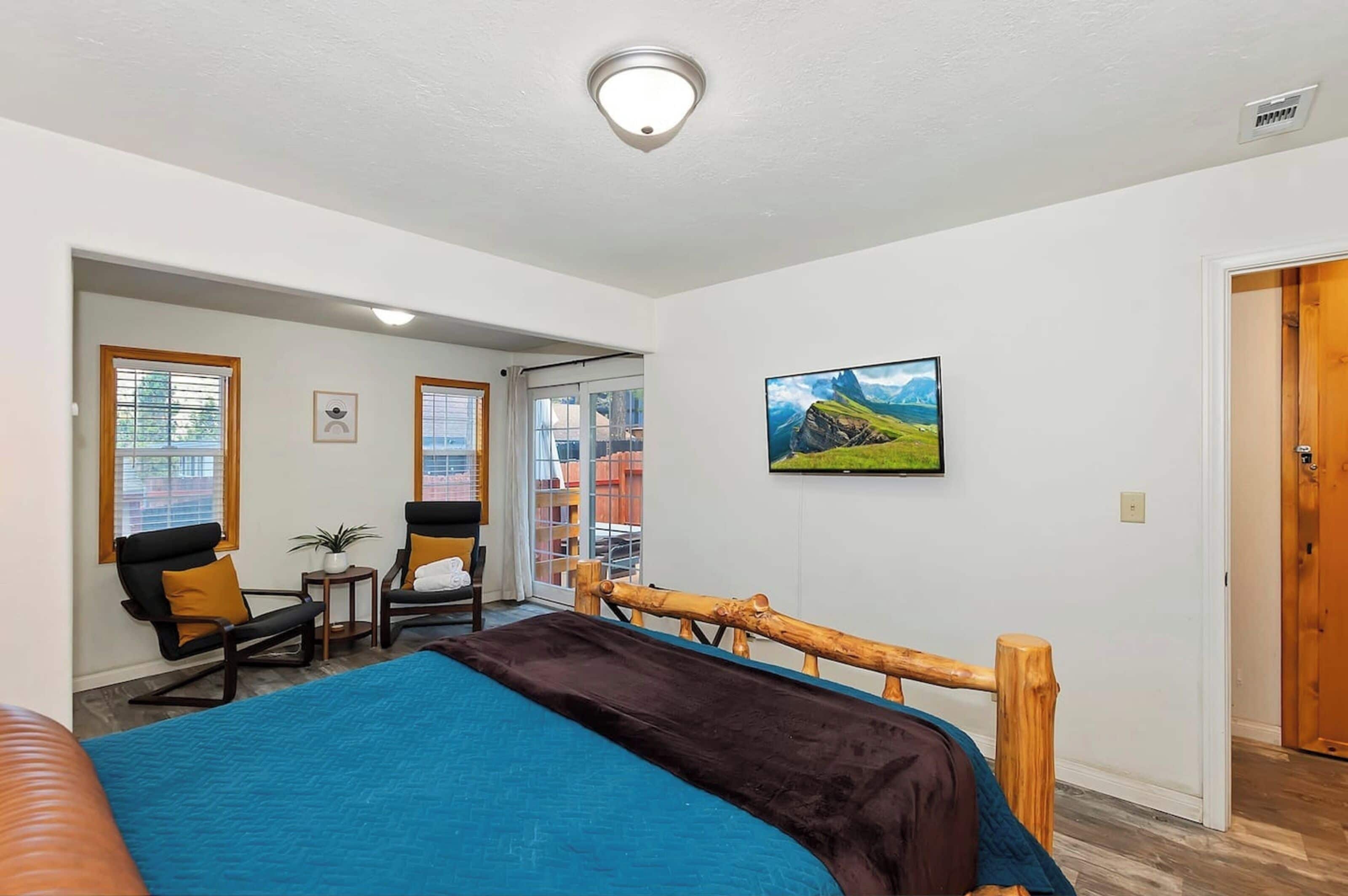 Een hotelkamer met een bed, een bureau met stoel, een raam met jaloezieën, een schilderij aan de muur en een deur.